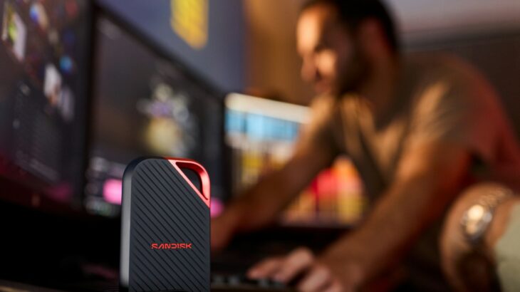 Portable ssd on desk with man working at computer.