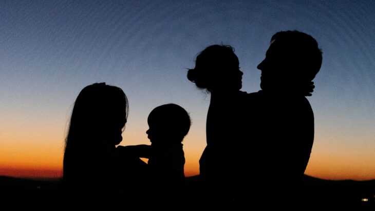 silhouette of 2 women and man standing during sunset